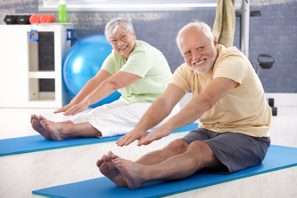 Older couple stretching on yoga mats.