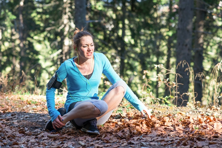 Young woman suffering from an ankle injury while exercising and running