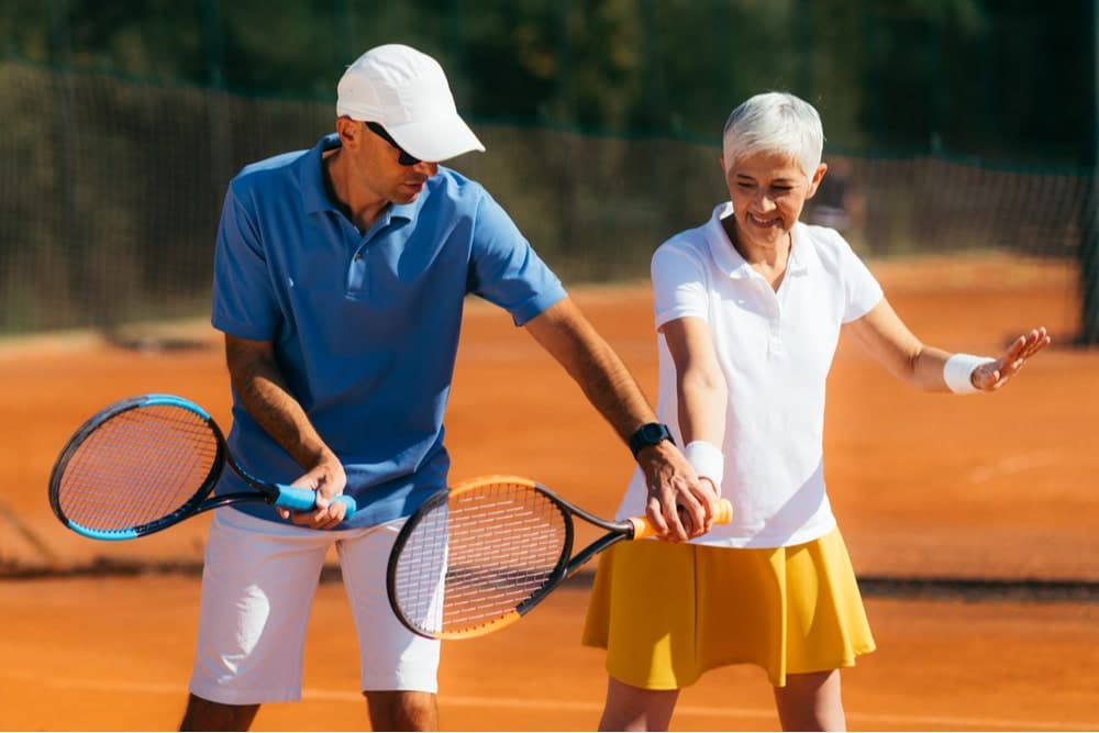 Older woman getting tennis lessons