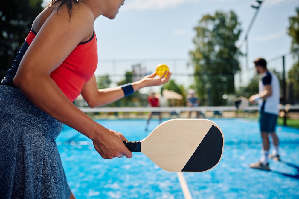 Woman holding a pickleball paddle and getting ready to serve